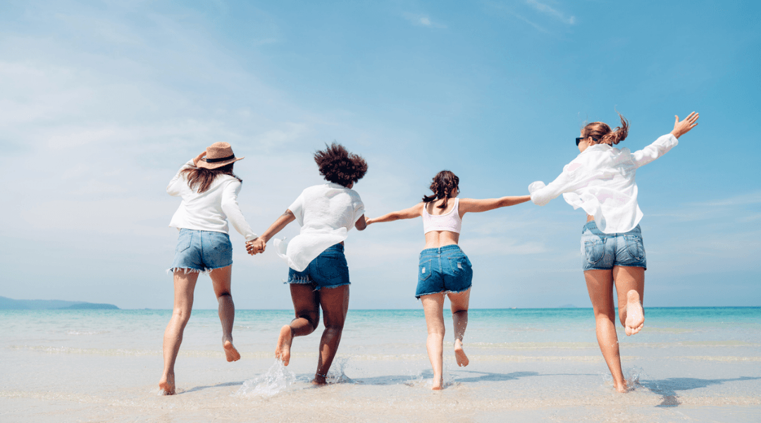 Friends running into the water on a sunny beach day