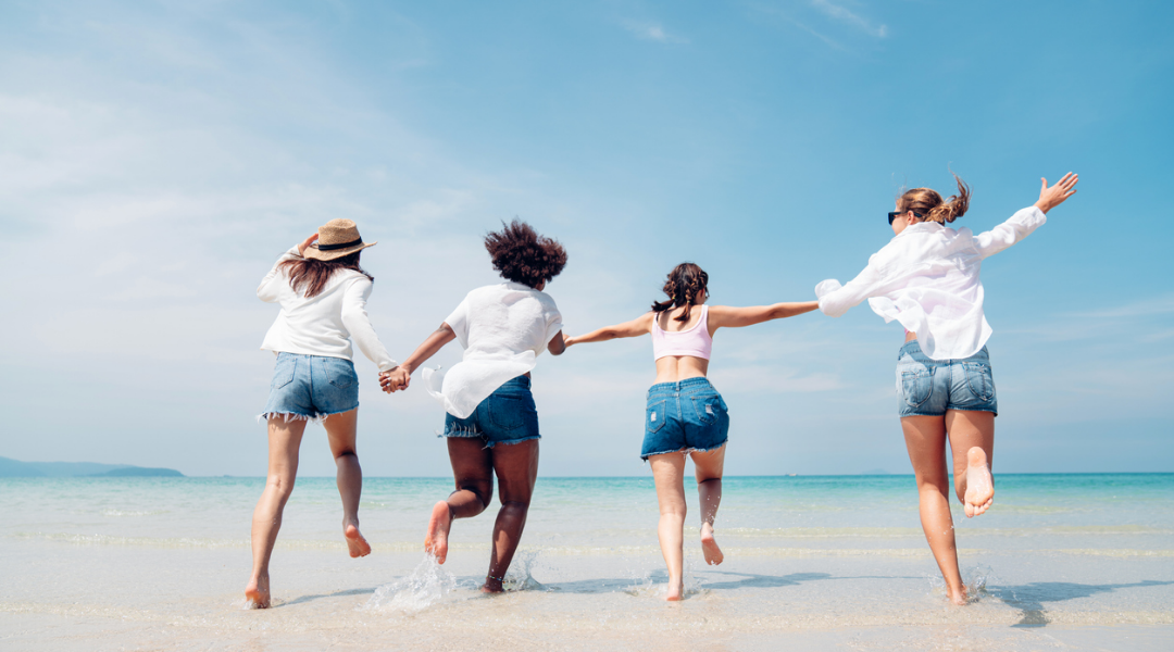 Friends running into the water on a sunny beach day