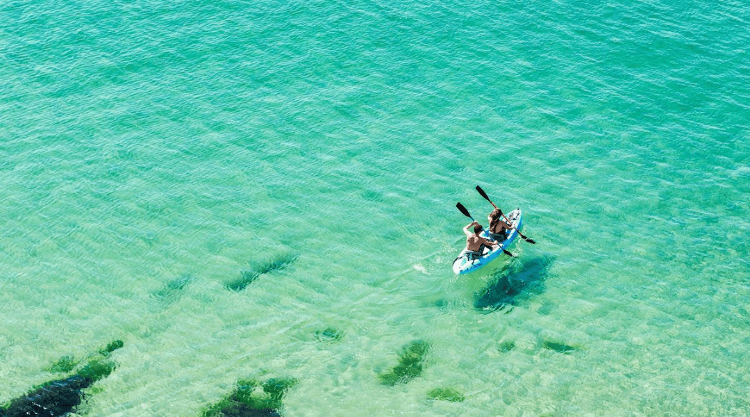 Kayakers paddling on clear turquoise water near Treasure Island