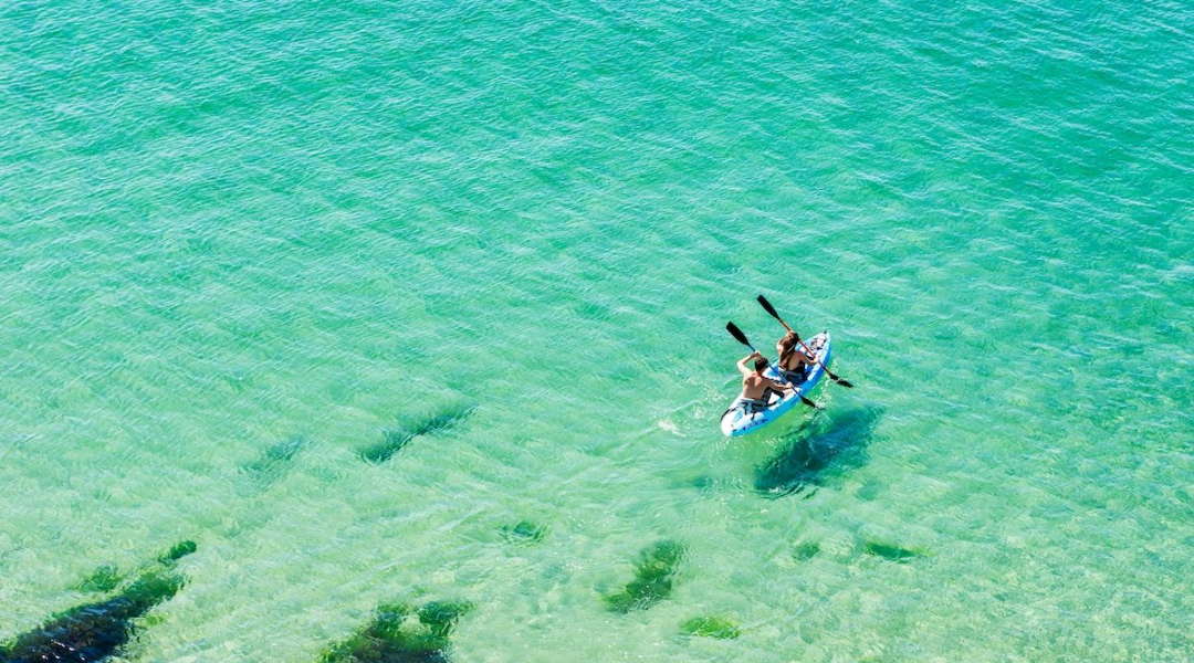 Kayakers paddling on clear turquoise water near Treasure Island